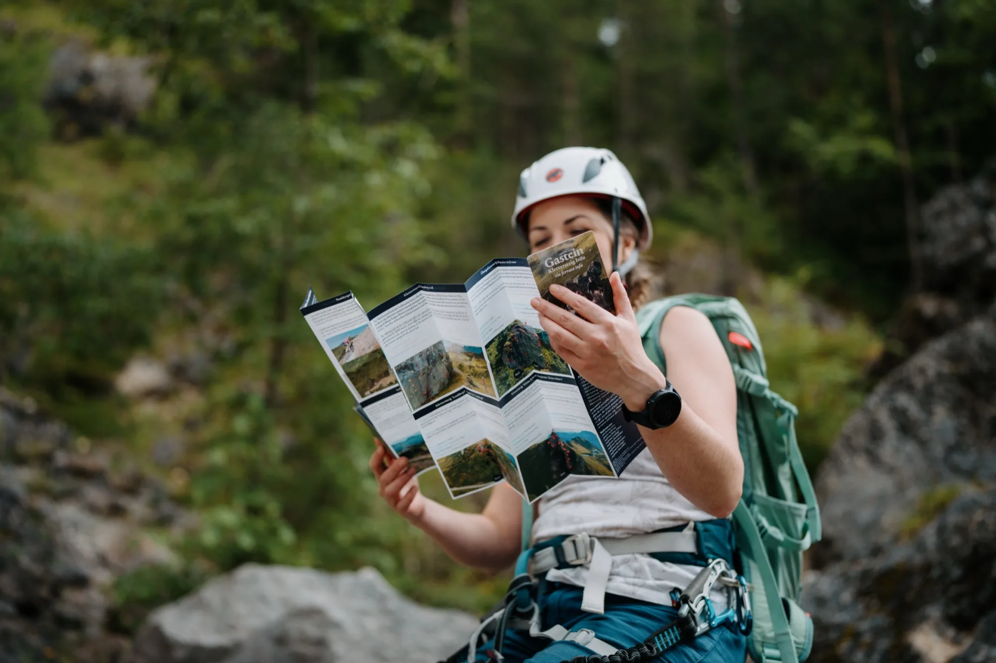 Arrampicatrice legge la guida alle vie ferrate della Gasteinertal – compatta mappa pieghevole TWIN-Card con info sui percorsi nella natura