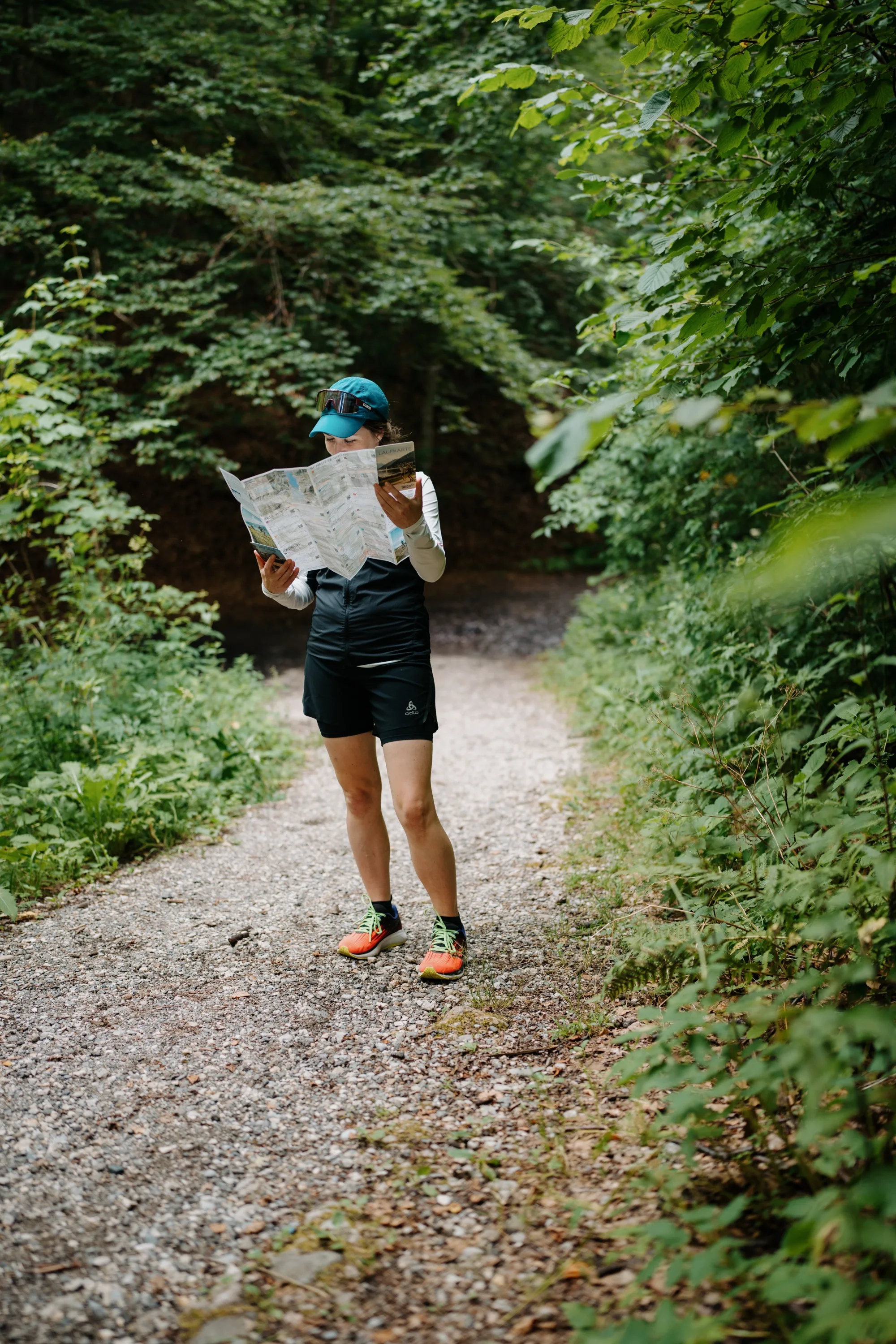 Carte de course Zell am See-Kaprun en action – une coureuse lit la carte pliée sur un chemin forestier